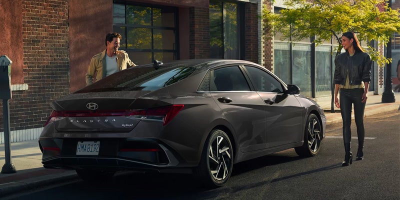 Hyundai Elantra Hybrid parked near a building with a couple standing beside it